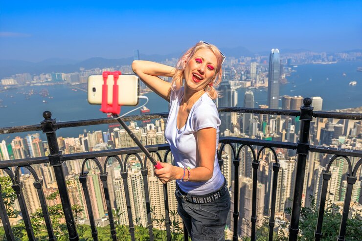 Photo woman taking selfie with mobile phone standing by railing against cityscape