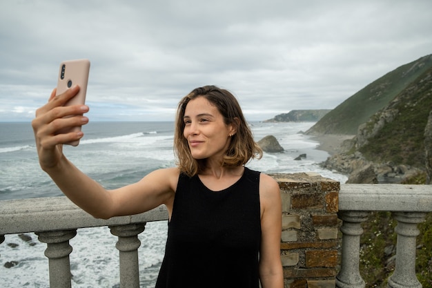 Donna che si fa un selfie con una costa montuosa nel nord della spagna