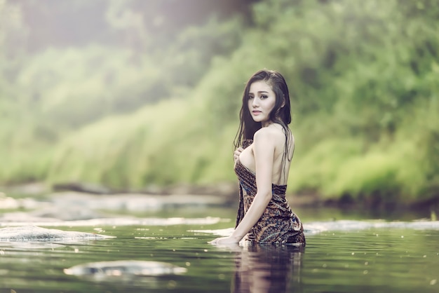 Woman taking shower outside in tropical green Bali garden with a lot flowers