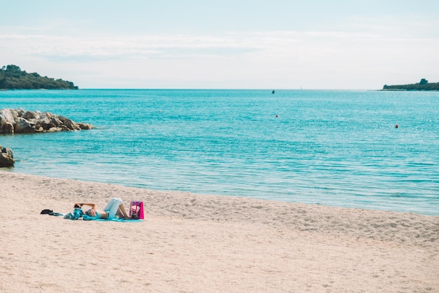 Woman taking sunbathing at sea beach laying on blanket