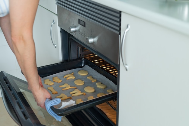 Woman taking a tray of freshly baked halleween cookies out of the oven domestic life copy space