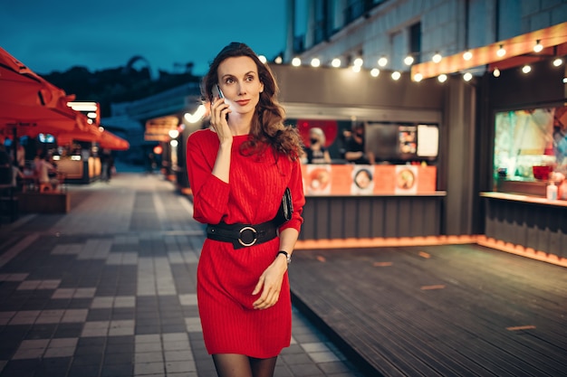 Woman talk on smartphone and walk in evening city