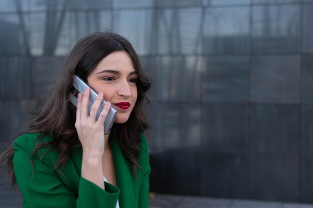 검은 벽 앞에서 휴대 전화로 통화하는 여성
