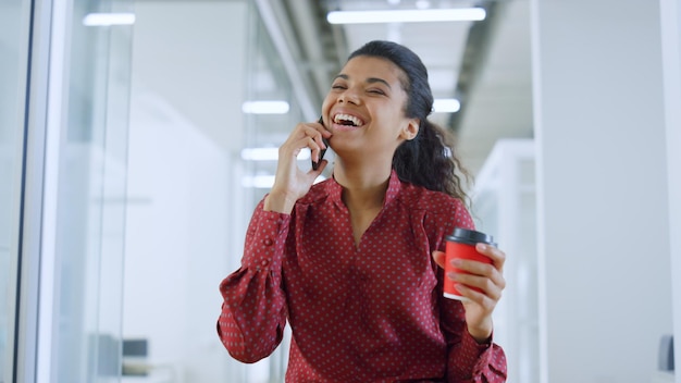 A woman talking on a cell phone and holding a coffee cup