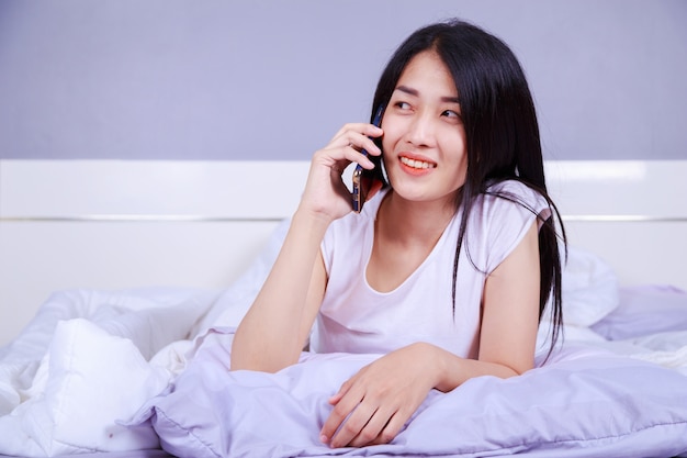 женщина, разговариваете по мобильному телефону на кровати в спальне