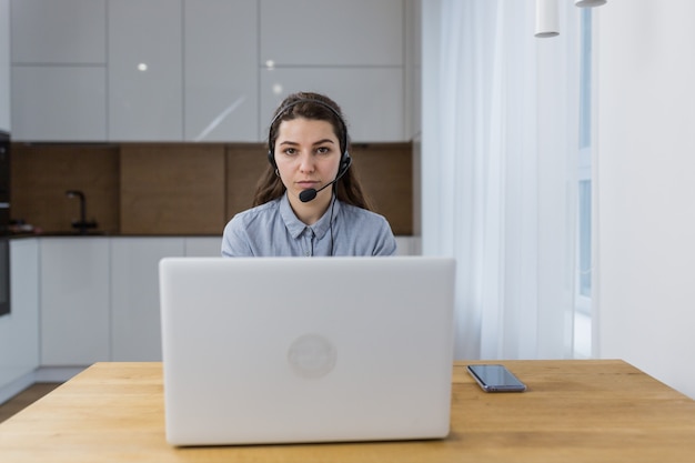 オフィスで、ノートパソコンの本を通してヘッドセットで話している女性