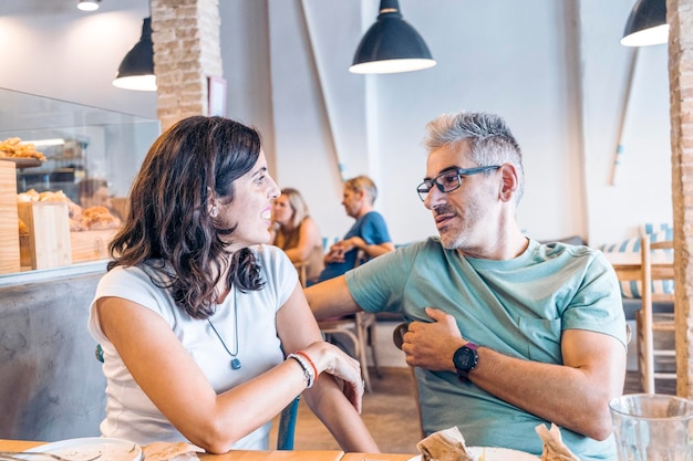 Woman talking to man sitting at table in restaurant