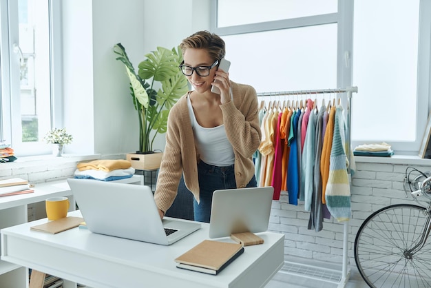 a woman talking on a phone in front of a laptop and a shirt that says  she is talking on the phone