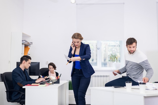 A woman talking over the phone in an open space office while walking around