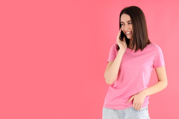 Woman talking on the phone on pink background