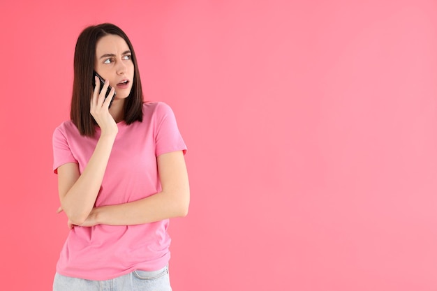 Woman talking on the phone on pink background