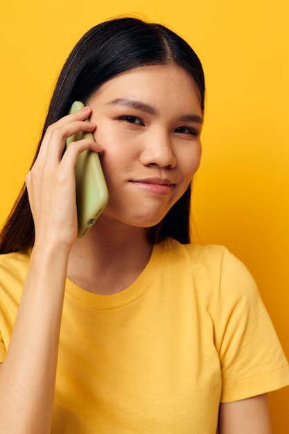 Woman talking on the phone posing technology yellow background unaltered
