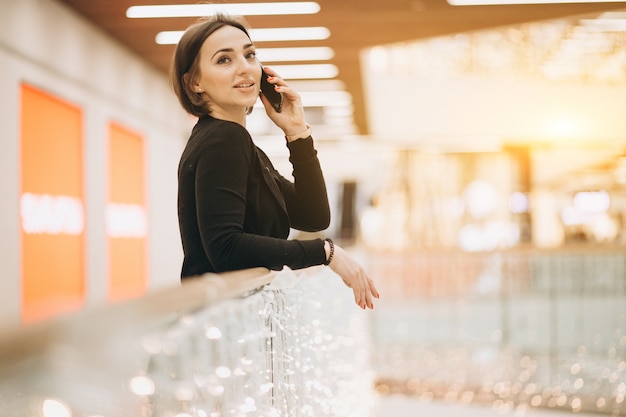 Женщина разговаривает по телефону в торговом центре