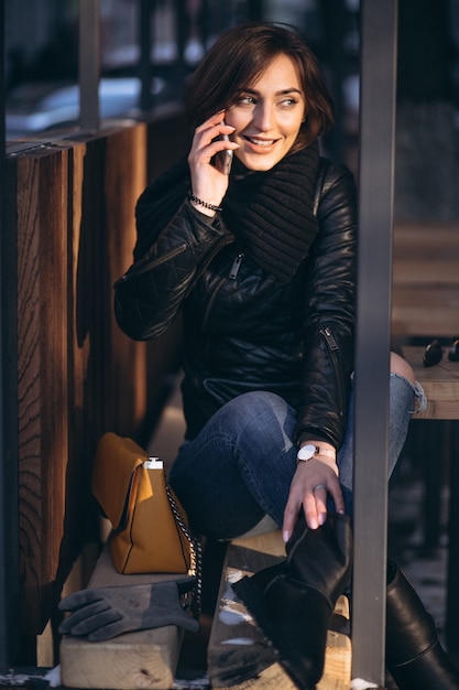 Woman talking on the phone and sitting on a bench in the street