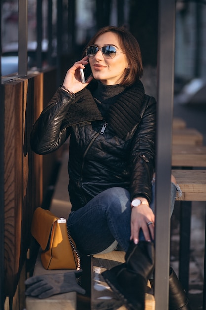 Woman talking on the phone and sitting on a bench in the street