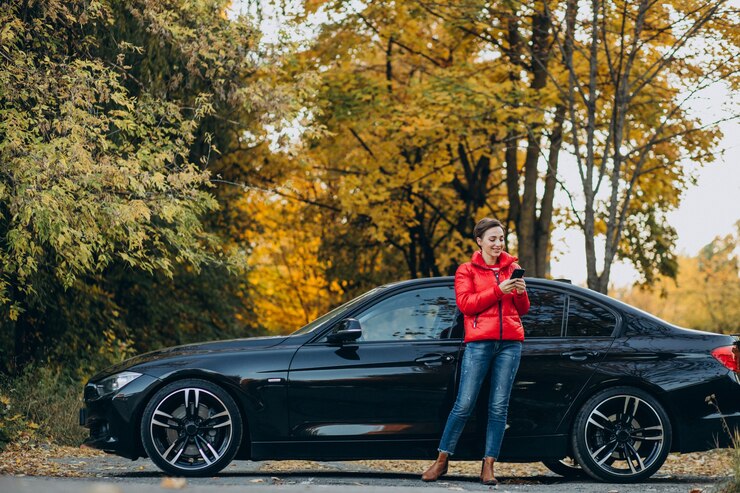 Photo woman talking on the phone and standing by her car
