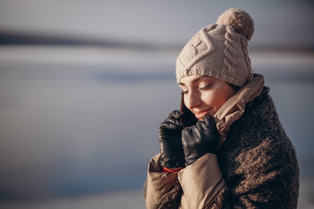 Woman talking on the phone in winter by the lake