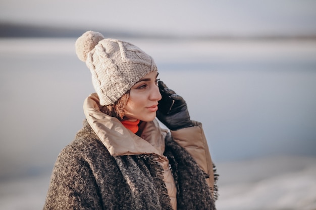 Woman talking on the phone in winter by the lake