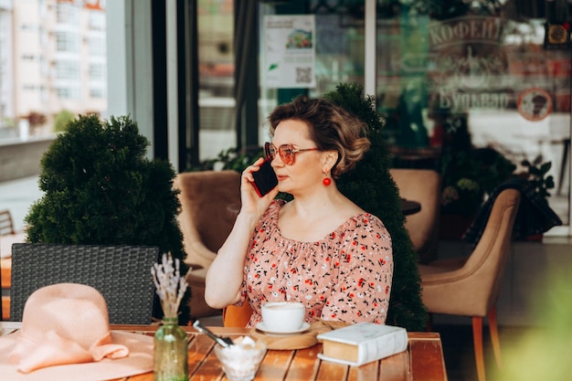 A woman talking on the phone A woman with a mobile phone is sitting in a cafe a woman in a dress and a hat in a cafe