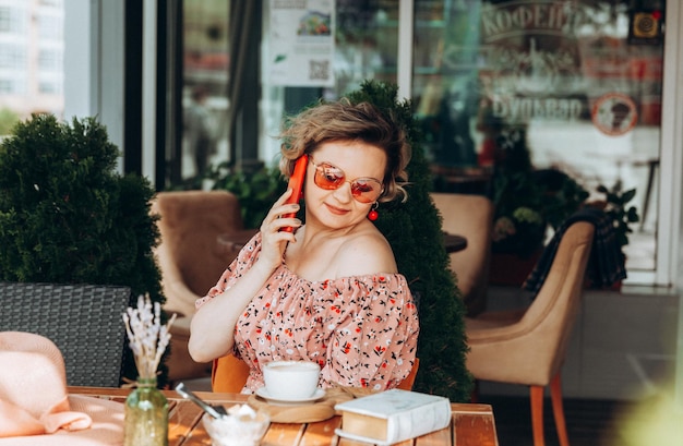 A woman talking on the phone A woman with a mobile phone is sitting in a cafe a woman in a dress and a hat in a cafe