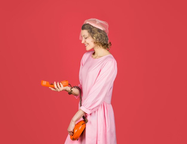 Woman talking on retro phone smiling woman in pink dress with telephone handset happy woman holds