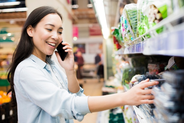 Donna che parla sullo smartphone in drogheria