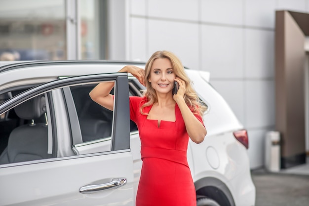 Photo woman talking on smartphone near car