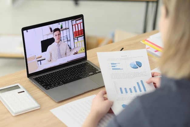 Woman talks to business partner via video call in corporate office closeup online conference