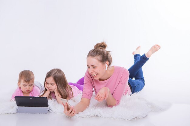 Woman talks on phone through headset and children watch cartoon on tablet