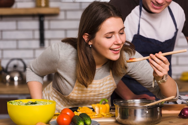 Photo woman tasting food while cooking with boyfriend