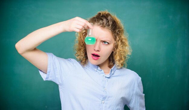 Woman teacher performing experiment with bulb and liquid Chemistry lesson Chemistry lab Interesting and fascinating Explore chemistry Girl observing chemical reaction chalkboard background