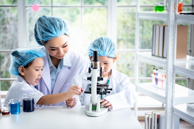 여자 교사 실험실에서 어린이 학생들을 위해 과학 실험이 수행되고 있습니다.