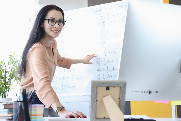 Woman teacher showing math formulas in computer screen