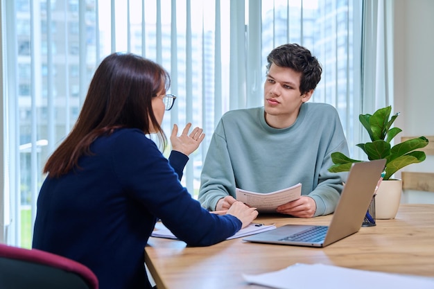 woman teacher talking helping testing male teenage student
