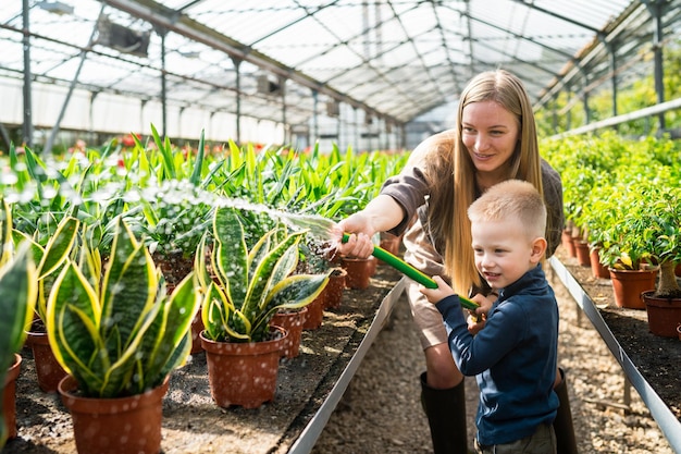 Woman teaches her son to water the plants