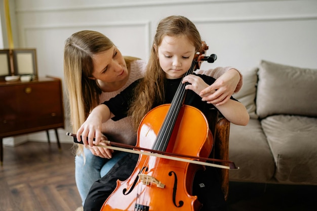 Woman Teaching a Girl How to Play Cello Stock Photo