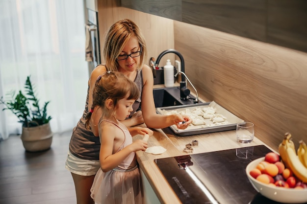 A woman teaching her little daughter the art of making cookies Mother teaching daughter to cook