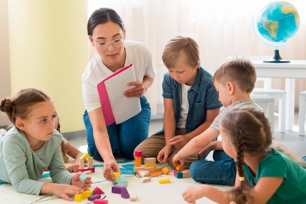 Foto donna che insegna ai bambini un nuovo gioco all'asilo