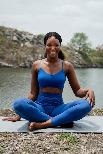 Foto donna che insegna una posa di yoga all'aperto