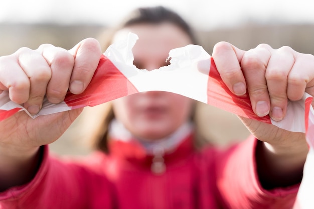 Woman tearing apart red white guard signal tape with her handsEnd of quarantine and selfisolation due to covid19 coronovirus pandemic Exit from home to street and walk in the fresh air in nature