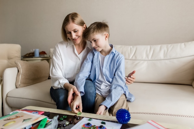 Женщина и подросток играют в настольную игру, улыбаясь