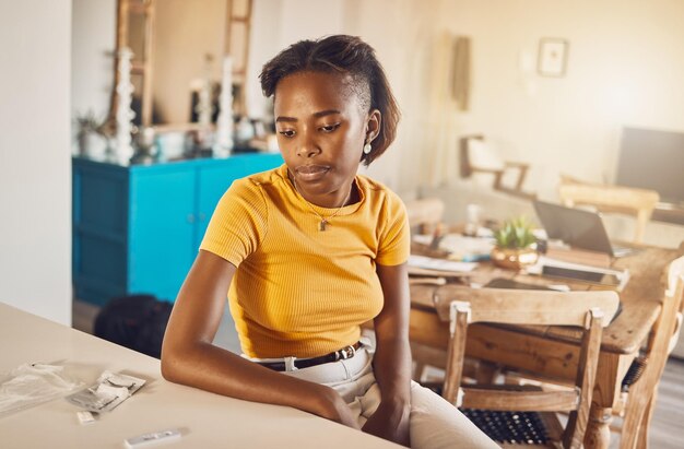 A woman test for covid waiting for the results from the kit at home Young casual African woman looking at her coronavirus or infection diagnosis from self testing equipment in her house