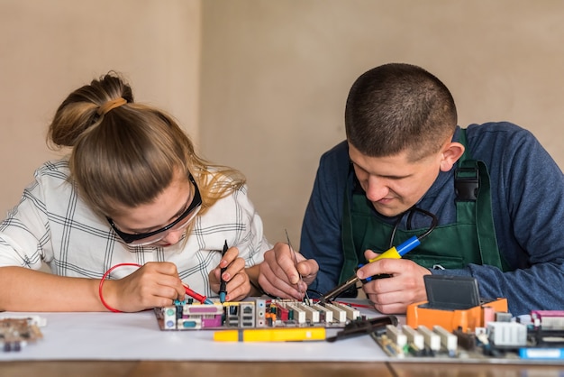 Woman testing motherboard and man repairing it