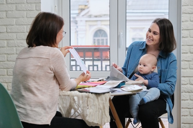 Woman textile designer and young mother with baby choosing fabrics