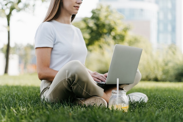 Woman texting laptop sitting on the grass