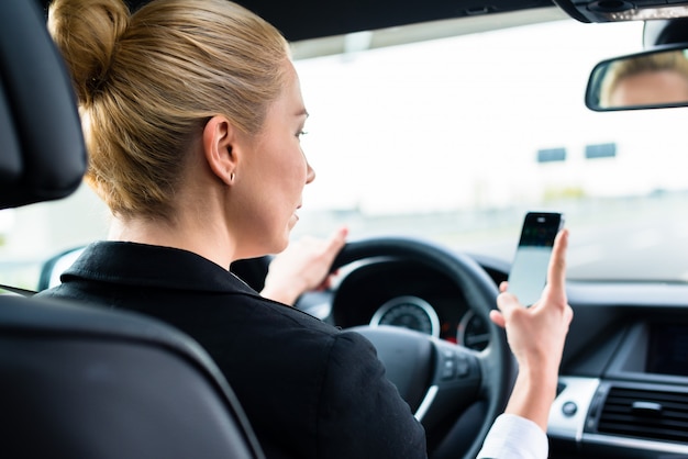 Женщина текстовых сообщений на свой телефон во время вождения на машине