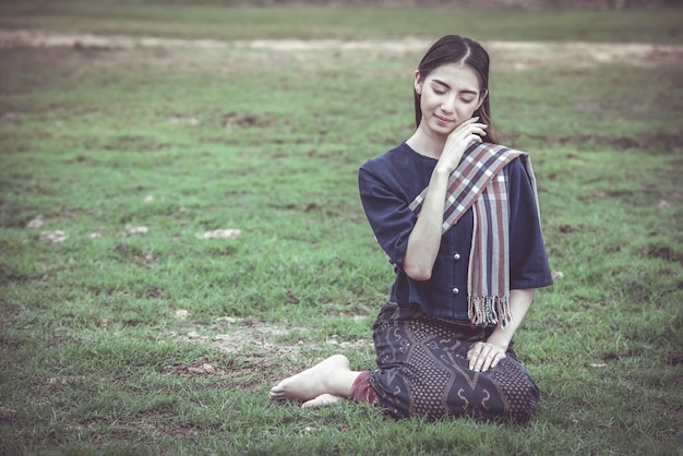 Woman on Thai traditional clothes sitting on the grass