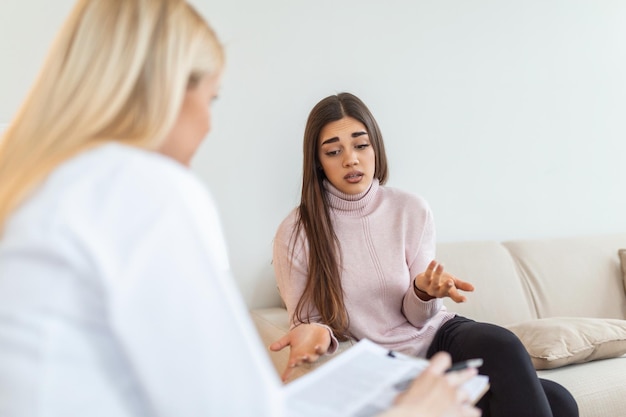 Woman at therapy session Attentive psychologist Attentive psychologist holding pencil in her hands making written notes while listening to her client