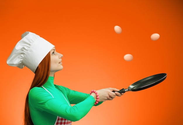 Woman throwing eggs in the air and catching it on frying pan