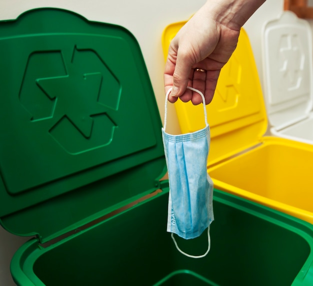 The woman throwing the medical mask into one of three trash bins